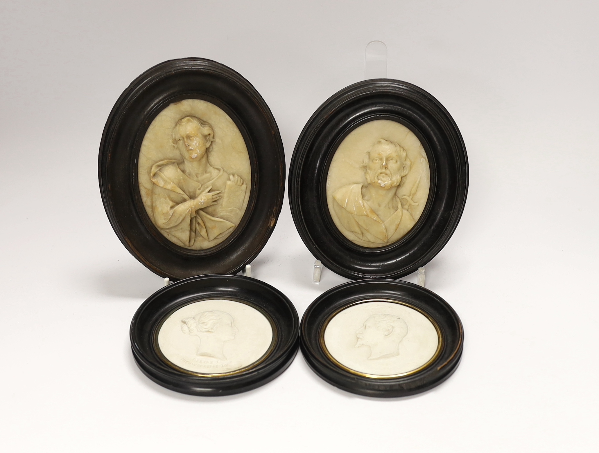 A pair of 19th century alabaster relief carved religious plaques and a pair of Sevres biscuit porcelain portrait plaques of Louis Napoleon and Eugene, housed in ebonized frames, largest overall 16cm high